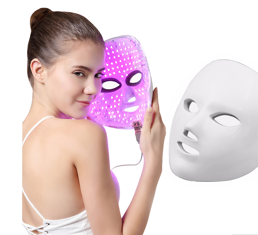 The LED mask lit in purple, held next to the unlit white mask
